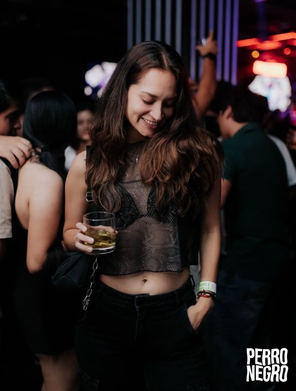 Una chica con un trago en la pista de Perro Negro
